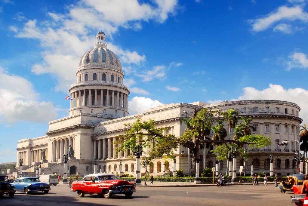 Classic american cars in front of hostoric building in Cuba