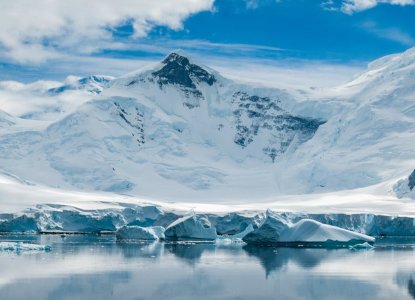 calm reflection in bay in Antarctica with snowy mountains down to waters edge