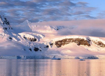 Snowy low-light landscape of Antarctica with calm bay