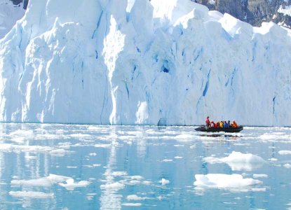 zodiac with tourists in front of a glacier in Antarctica