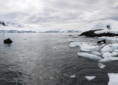 Icy shoreline in Mikkelsen Harbour in Antarctica with snowy mountains