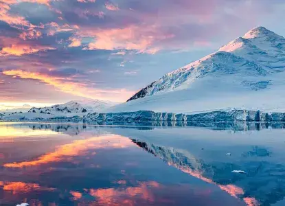 calm bay in Antarctica with midnight sun colouring snowy mountain